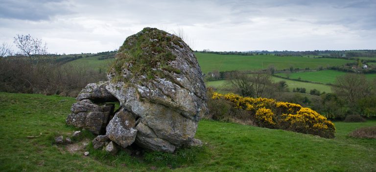 The stone of the Divisions (AKA the Cat Stone) on the Hill of Uisneach in County Meath is is possibly the most signifcant ancient monument in the whole country. Firstly, legend say that this is the burial place of Queen Eriu, Queen of the Tuatha de Danann (A powerful, magical race that inhabited Ireland before the Celts). She was defeated and mortally wounded in a battle with the Celtic King, Amergen granted her a dying wish. He promised her that the island would bear her name forever – The Gaelic name Eriú was later changed by the Vikings into “Eriú’s Land”, or Ireland. This 30-ton stone looks more like a giant bolder that has been cracked into several pieces. The splits are believed to represent the ancient divisions of Ireland. A book called Beneath the Shadow of Uisneach, says that it was from here that the five ancient provinces of Ireland met, symbolising this as the centre of Ireland. The stone’s Irish name depicts this: Ail na Mireann (“Stone of the Divisions”). The division were first made by the Fir Bolg. It is on this hill that the first fire was lit for the ancient festival of Bealtaine. It was said that a fire lit at the summit here could be seen all over Ireland, and that all fires were lit from this one. This hill was also the gathering place of the kings of Ireland.