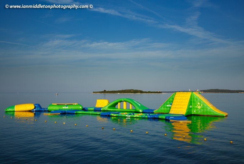 Morning at Puntižela Beach, Štinjan north of Pula. View of the Brijuni Islands and the childrens inflatable playground on the water.