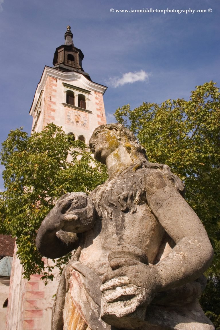 Statue of Mary Magdalene on Bled Island with the bell tower behind.