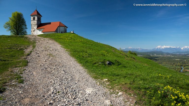 The path leadning up to church of Saint Anna (Sveta Ana) with Ljubljanica River and Kamnik Alps in the background. Taken in spring. Sveta Ana is perched upon an exposed hill overlooking the Ljubljansko Barje (Ljubljana marshes) near the village of Preserje. The views from this hill are spectacular and many locals seem to come here for the evening.